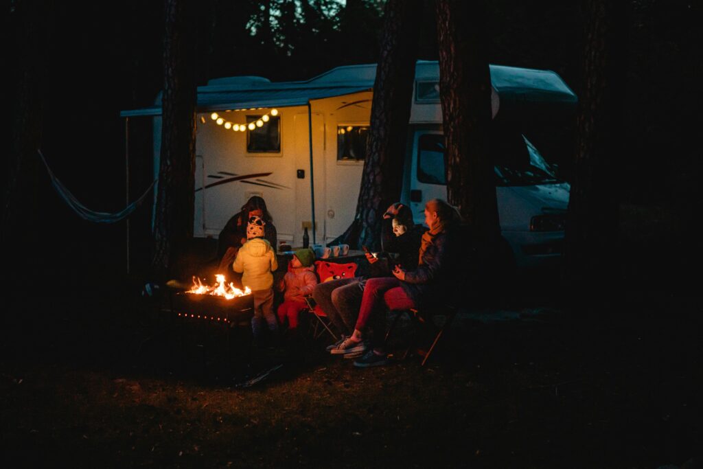 camping resources, Family enjoying a warm night by the campfire beside their campervan in Lithuania.