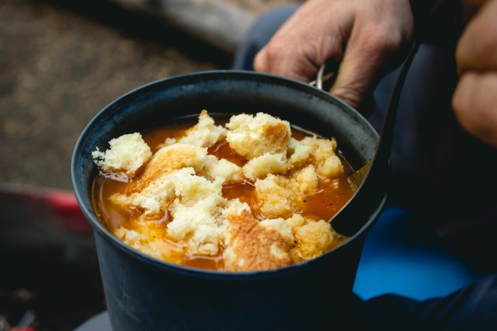 A warm and hearty stew with fresh bread outdoors, perfect for camping meals.