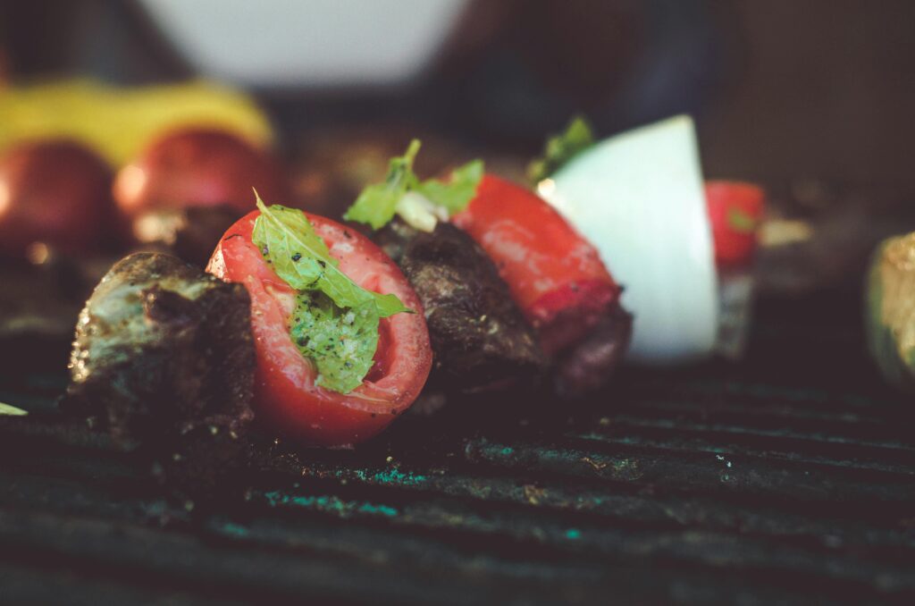 Mouthwatering grilled skewers with meat, tomatoes, and onions on a barbecue.